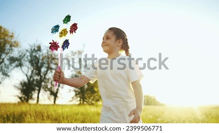 child girl running with windmill a toy in the park. happy family kid dream concept. daughter girl playing with a toy windmill in nature. childhood freedom wind outdoors concept