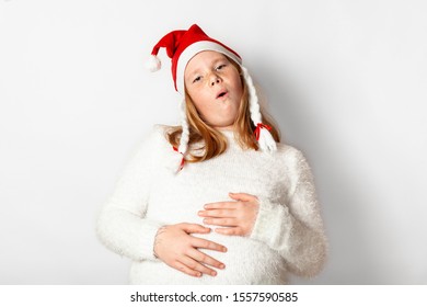 Child Girl In Santa Hat Over Eat About New Year's Holidays, Gluttony For Christmas.