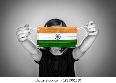 A Child Girl Show A Protective Medical Mask Against Bacteria And Viruses With The Flag Of India.