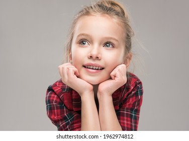Child girl surprised holds her face and dreamily looks to the side. Little Baby  in a red dress. Children's products , clothing and accessories . Expressive facial emotions