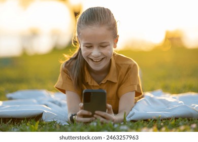 Child girl texting with her friend on cellphone outdoors in summer park - Powered by Shutterstock