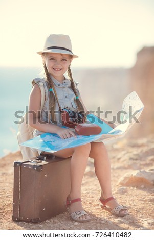 child girl traveler. trip alone. girl walking with camera and suitcase on nature by sea. travel, vacation, holidays