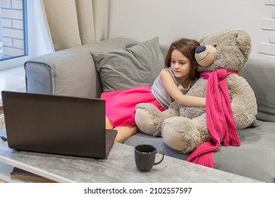 Child Girl Watching Laptop Screen, Hugging Teddy Bear. Concept Of Distance Learning, E-learning, And Leisure Of Modern Children At Computer.