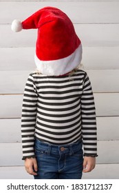 Child Girl Wearing Santa Claus Hat Pulled Over Face, Concept Waiting For Christmas, Close-up