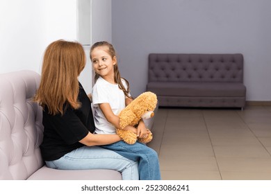 Child girl with a woman mother in the clinic, waiting for a doctor appointment. Mom with a daughter in a modern hospital before receiving a pediatrician. Kid 6-7 year old, check up before school - Powered by Shutterstock