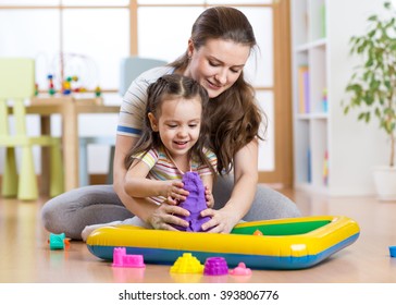 Child girl and woman mould with kinetic sand in playschool or daycare - Powered by Shutterstock