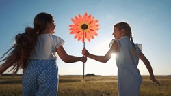 Child Girls Running With Windmill A Toy Lifestyle In The Park. Happy Family Kid Dream Concept. Daughters Girls Playing With Toy Windmill In Nature. Childhood Freedom Wind Lifestyle Concept Outdoors