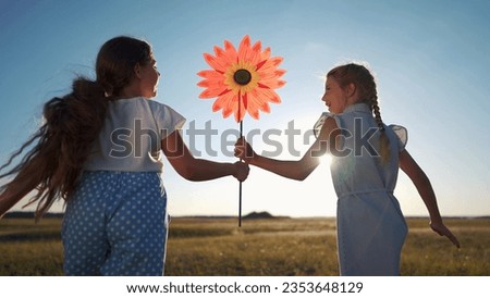 child girls running with windmill a toy lifestyle in the park. happy family kid dream concept. daughters girls playing with toy windmill in nature. childhood freedom wind lifestyle concept outdoors
