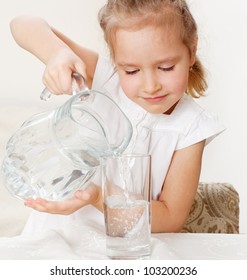 Child With Glass Pitcher Water. Little Girl Drinking Water At Home