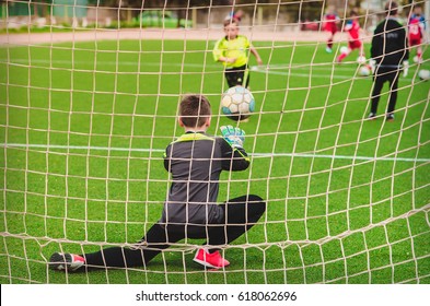 A Child, A Goalkeeper In Football On A Green Field In The Game Plays The Ball Off