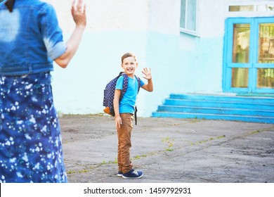 The Child Goes To School. Boy In The Morning, Goes To School. Portrait Of A Happy Child With A Briefcase On His Back. The Concept Of A Student Going To School And Waving My Mom Goodbye.copy Space.