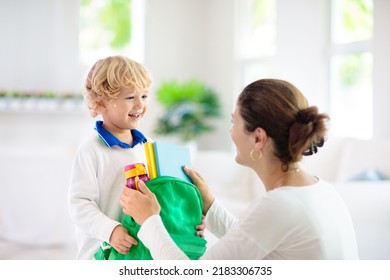 Child going back to school. Mother and kid getting ready for first school day after vacation. Little boy and mom going to kindergarten or preschool. Student packing books, apple and lunch in backpack. - Powered by Shutterstock