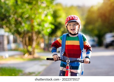 Child Going To School On Bike. Kids Ride Bicycle. Safe Way To Elementary School. Little Boy With Backpack On Red Bike Wearing Safety Helmet. Healthy Outdoor Activity For Young Student.