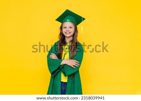 The child is a graduate. A little girl in a graduate hat on a yellow isolated background. Happy graduation to a little girl. Graduation from elementary school.