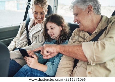 Child, grandparents and phone on road trip in car backseat streaming movie, elearning or helping with education game. Child, man and woman uber happy on travel journey and checking destination online