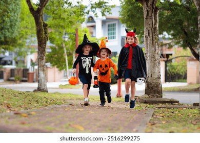 Child in Halloween costume. Kids trick or treat on suburban street. Little boy and girl with pumpkin lantern and candy bucket. Baby in witch hat. Autumn season holiday fun.  Friends play outdoor. - Powered by Shutterstock