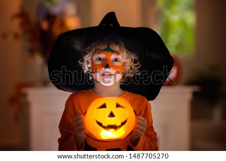 Child in Halloween costume. Kids trick or treat. Little boy with pumpkin face painting and lantern.
