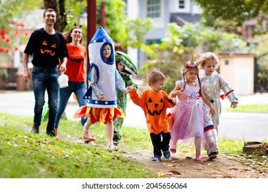 Child in Halloween costume. Mixed race Asian and Caucasian kids and parents trick or treat on street. Little boy and girl with pumpkin lantern and candy bucket. Baby in witch hat. Autumn holiday fun. - Powered by Shutterstock