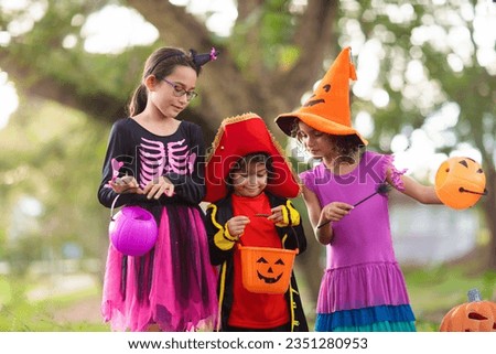 Child in Halloween costume. Mixed race kids and parents trick or treat on street. Little boy and girl with pumpkin lantern and candy bucket. Baby in witch hat. Autumn holiday fun.
