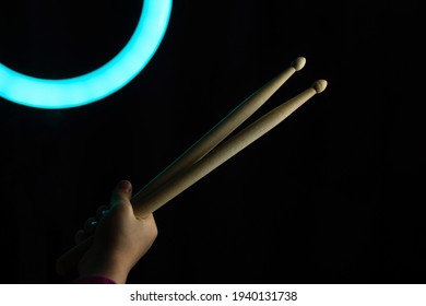 Child Hand Hold Wooden Drum Sticks On Black Backlit Blue Background. Rock Music Concept. Advertising Drum Lessons For Children. Unrecognizable. Soft Focus