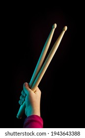 Child Hand Hold Wooden Drum Sticks On Black Backlit Blue Background. Rock Music Concept. Unrecognizable. Soft Focus.