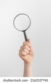 Child Hand Holding Black Magnifying Glass. White And Gray Background With Copy Space