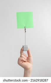 Child Hand Holding Green Blank Reminder Or Paper Notes Above A White And Gray Background, Copy Space