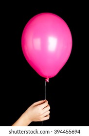 Child Hand Holding Pink Balloon Isolated On Black Background