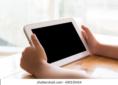 Child Hand Holding Tablet On Blurred Background
