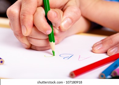Child hand with pencil and woman hand helping to write letters