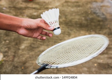 Child hand playing badminton on concrete court in rural