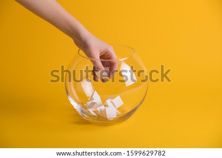 Child hand randomly picking a paper from a glass bowl, random name ballot, simple raffle