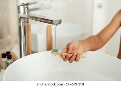 Child Hand Washing A Bamboo Toothbrush With Tap Water. The Concept Of Saving The Planet From Plastic, Introducing Children To Protect Nature. The Concept Of Zero Waste. Selective Focus