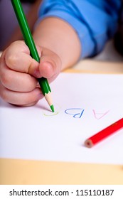 Child Hand Writing Letters With Green Pencil