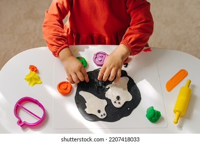 Child hands creating playdough funny monsters and scary  ghost for the holiday of Halloween. Sensory play for toddlers. Holiday Art Activity for Kids