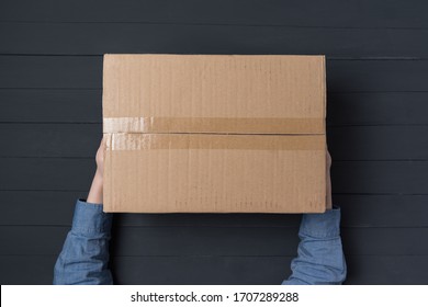 Child Hands Holding Large Cardboard Box. Delivery Of Parcels To House. Top View.