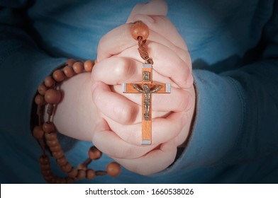 Child Hands Holding Rosary Beads And Cross While Praying.