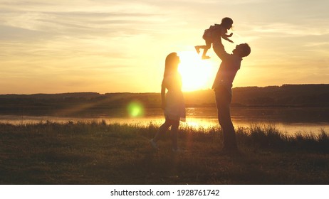Child in the hands of parents jumps from dad to mom and laughs. Happy family walk on the beach at sunset. Child, daughter, mom, dad play fun in park in park in sun. Family fantasies, childhood dreams. - Shutterstock ID 1928761742