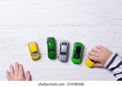 Child Hands Playing With Miniature Toy Cars, Wooden Background, Top View