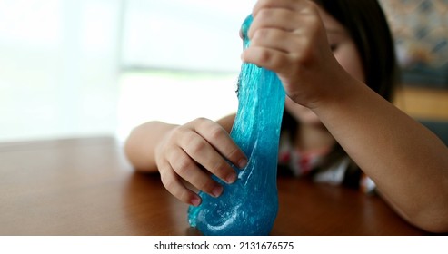 Child hands playing with slime goo. Little girl close-up hand and fingers with sticky elastic plasticine
