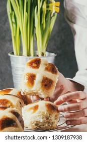 Child Hands Take Homemade Easter Traditional Hot Cross Buns On Cooling Rack On White Marble Table With Narcissus Flowers.