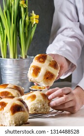 Child Hands Take Homemade Easter Traditional Hot Cross Buns On Cooling Rack On White Marble Table With Narcissus Flowers.