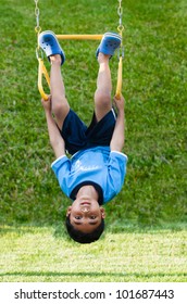 Child Hanging Upside Down On Monkey Bars In Playground