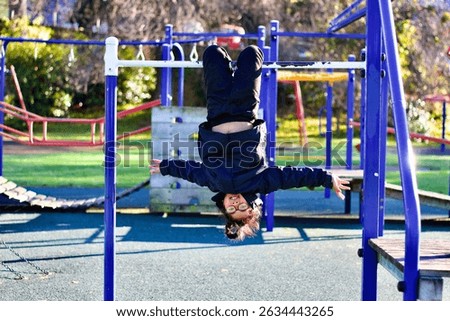 A child hangs upside down on playground equipment.