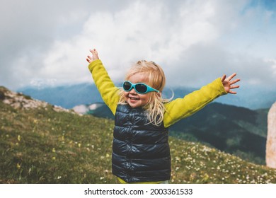 Child happy raised hands walking in mountains travel family vacations lifestyle 2 years old laughing toddler outdoor funny kids