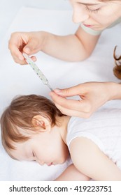 Child Has A High Temperature Or Fever. Sad Mother Measures The Temperature Of Baby Using A Thermometer. Closeup. Flu. 