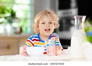 Child having breakfast. Kid drinking milk and eating cereal with fruit. Little boy at white dining table in kitchen at window. Kids eat on sunny morning. Healthy balanced nutrition for young kids. - Powered by Shutterstock