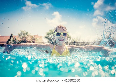 Child Having Fun In Swimming Pool. Kid Playing Outdoors. Summer Vacation And Healthy Lifestyle Concept