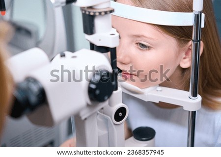 Child having his eyes checked with ophthalmic equipment