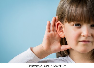 Child With Hearing Problem On Blue Background. Hearing Loss In Childhood, Symptoms And Treatment Concept. Close Up, Copy Space.